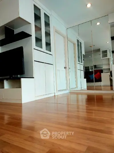 Modern living room with mirrored wall and sleek wooden flooring