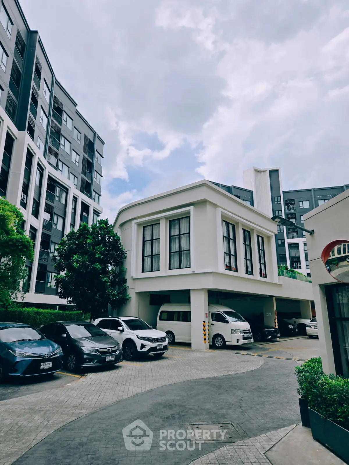 Modern apartment complex with parking area and sleek architectural design.