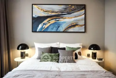 Stylish bedroom with modern decor and abstract art above the bed, perfect for relaxation.