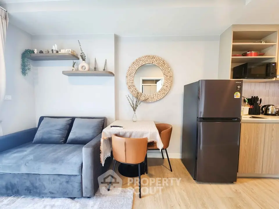 Modern living room with cozy sofa, dining table, and sleek kitchen appliances.