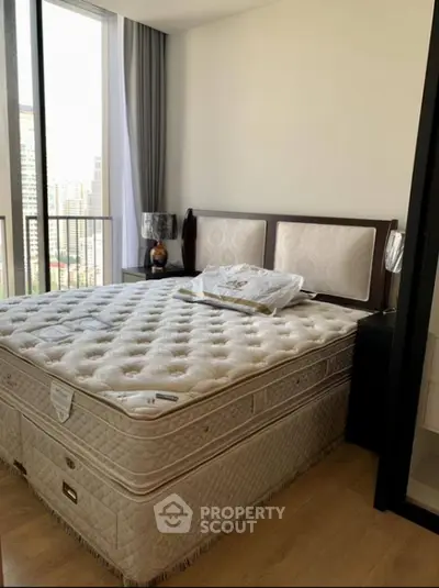 Spacious bedroom with large bed and city view from balcony.
