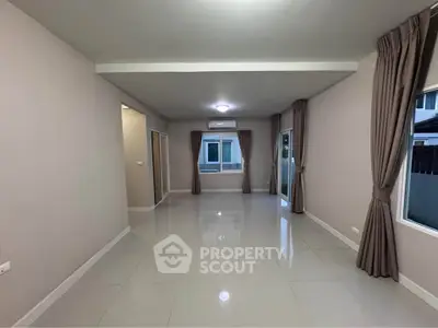 Spacious unfurnished living room with large windows and modern tile flooring.