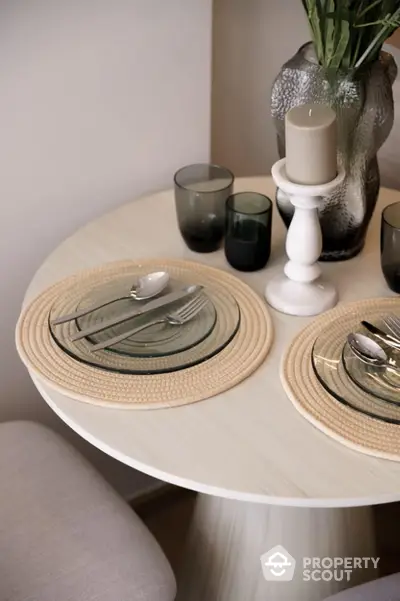 Elegant dining setup with glass plates and candle on a round table, perfect for cozy meals.