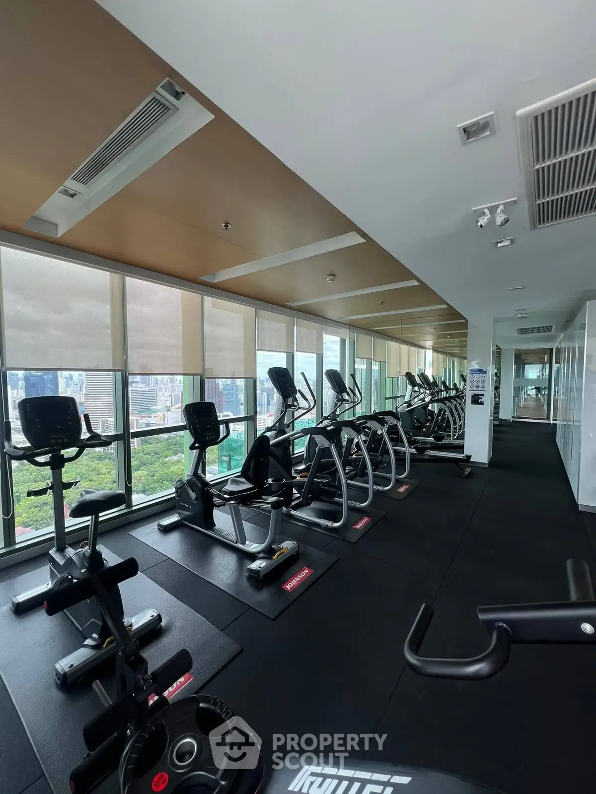 Modern gym with city view and state-of-the-art fitness equipment in luxury residential building.