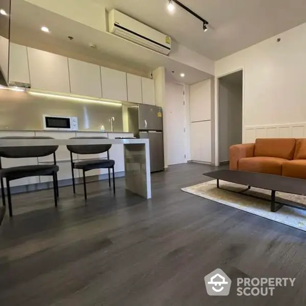 Modern open-plan living space with sleek kitchen, cozy sitting area, and ample natural light, perfect for urban living.