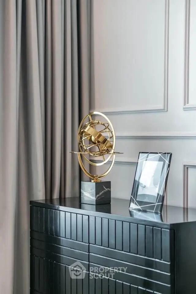Elegant interior decor with modern sculpture and sleek black cabinet in stylish living space.
