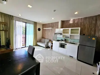 Modern open-layout living room with kitchen, featuring sleek appliances and natural light from balcony.