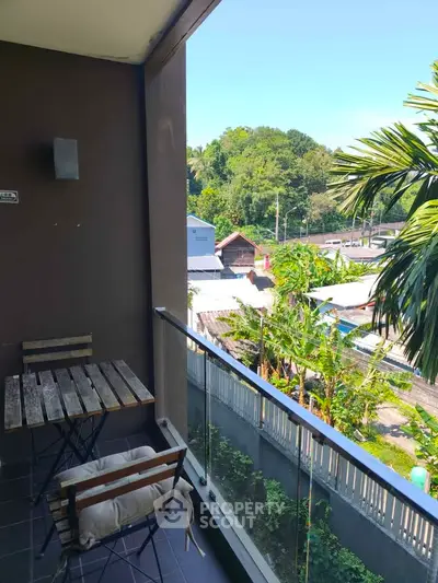 Charming balcony with lush green view, perfect for relaxation and outdoor dining.