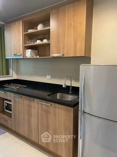 Modern kitchen with wooden cabinets, black countertop, and stainless steel appliances.