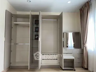 Spacious bedroom with modern wardrobe and vanity set, featuring ample storage and elegant design.