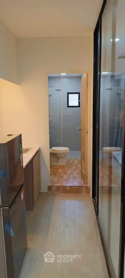 Compact apartment kitchen with adjacent bathroom, featuring modern appliances and sleek design.