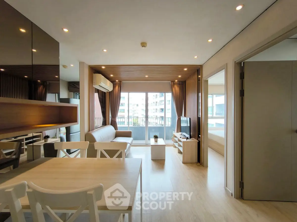 Modern living room with balcony view, featuring sleek furniture and ample natural light.