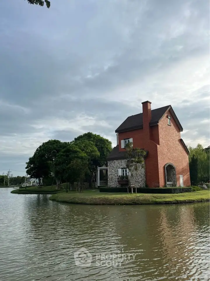 Charming brick house by a serene lake with lush greenery, perfect for tranquil living.