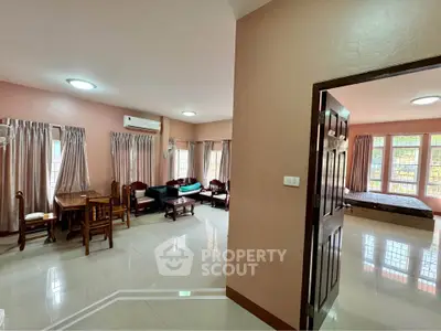 Spacious open-plan living room with dining area and adjacent bedroom, featuring large windows and modern furnishings.