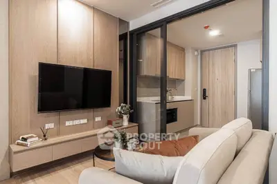 Modern living room with sleek TV setup and cozy kitchen in open layout apartment.