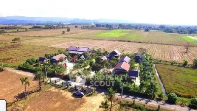 Aerial view of a rural property with multiple houses surrounded by fields and greenery.