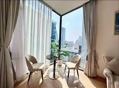 Bright corner unit with floor-to-ceiling windows offering stunning city views, featuring elegant seating area.