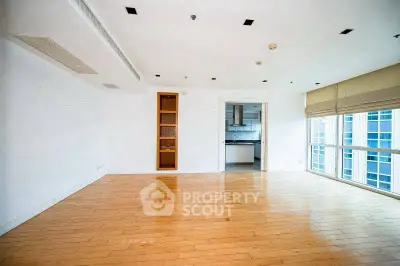 Spacious living room with wooden flooring and large windows in modern apartment.