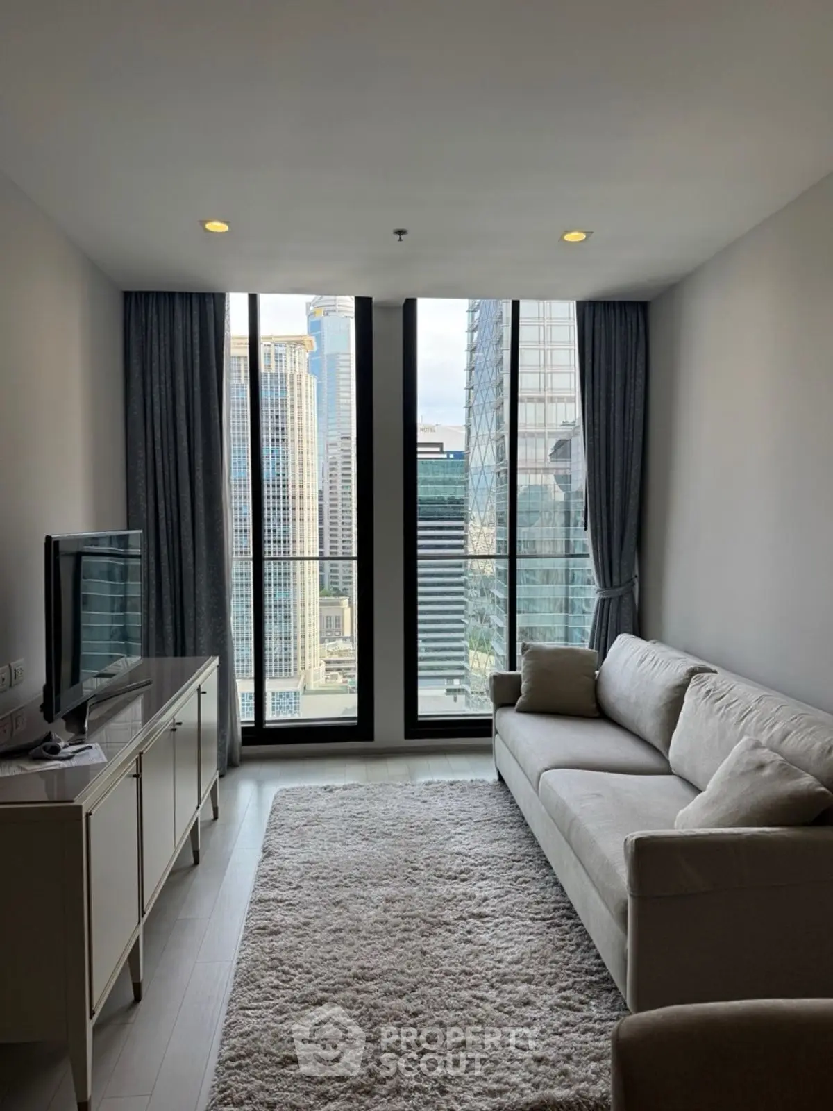 Modern living room with city view, featuring a cozy sofa and sleek TV setup.