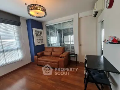 Modern living room with stylish decor and natural light, featuring a cozy brown sofa and sleek wooden flooring.