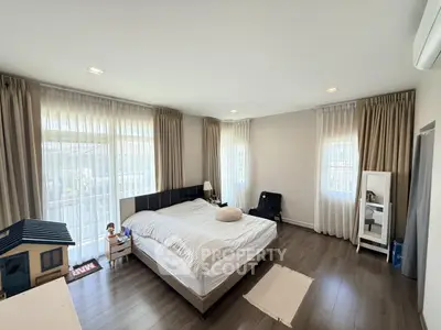Spacious bedroom with large windows and modern decor, perfect for relaxation and comfort.
