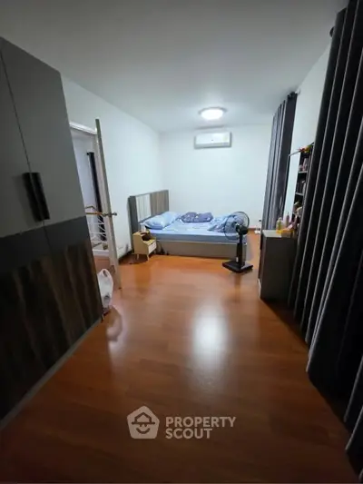 Spacious bedroom with wooden flooring and modern furnishings, ideal for comfort and relaxation.