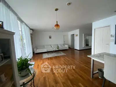 Spacious living room with hardwood floors and modern decor in a bright apartment.
