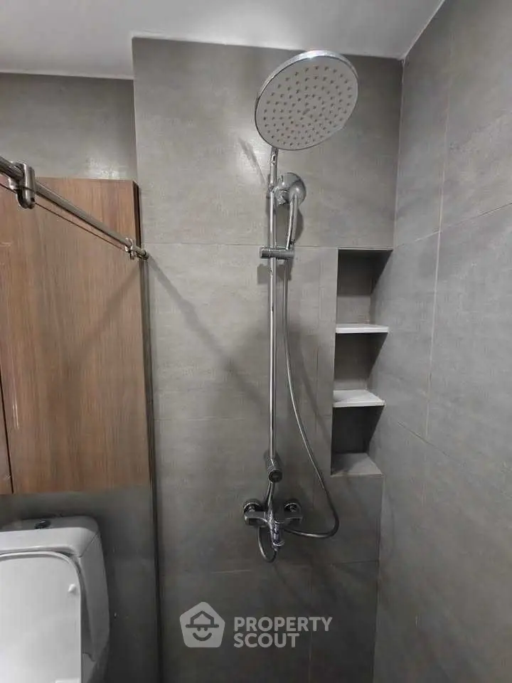 Modern bathroom with sleek shower fixtures and built-in shelving.