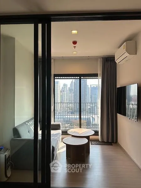 Modern living room with city view, featuring sleek furniture and large windows for natural light.
