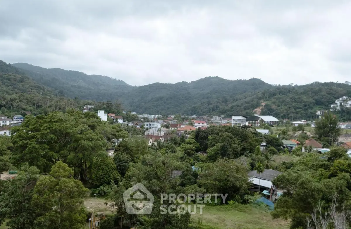 Scenic view of lush green landscape with residential area and mountains in the background.