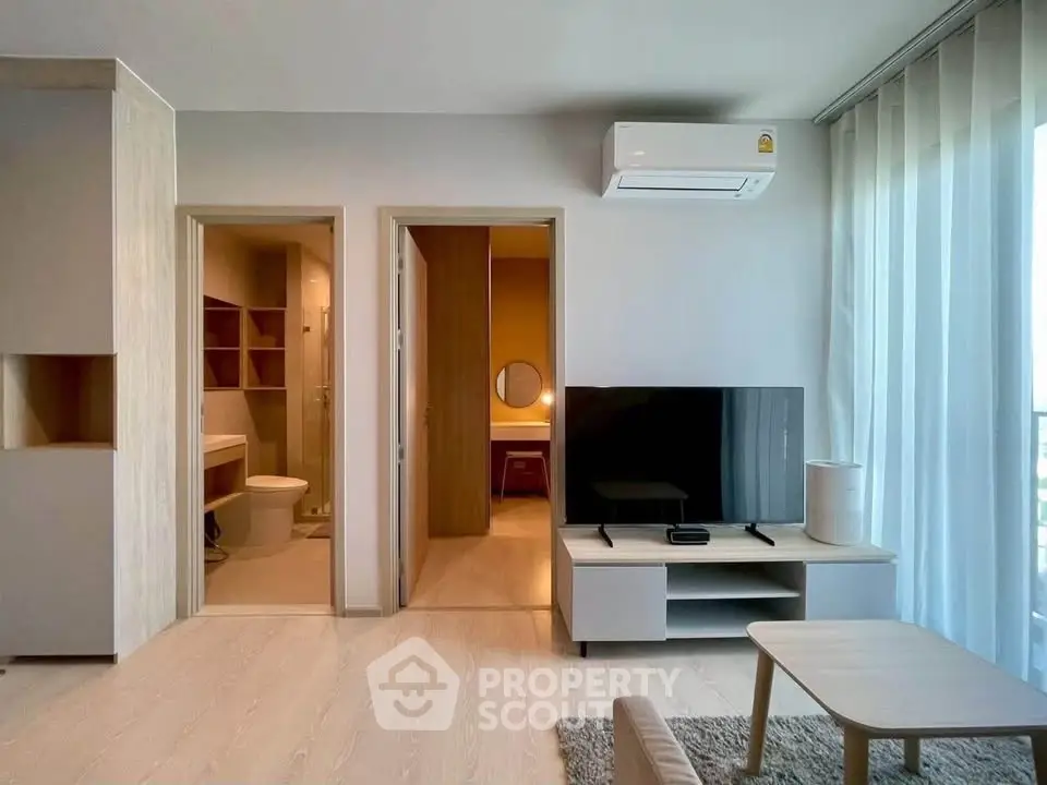 Modern living room with TV, air conditioning, and view into bathroom and bedroom.