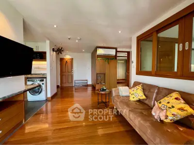 Spacious living room with wooden flooring, cozy sofa, and modern appliances in a stylish apartment.