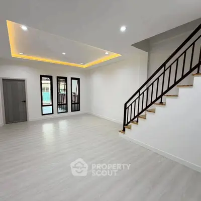 Spacious modern living room with elegant staircase and large windows