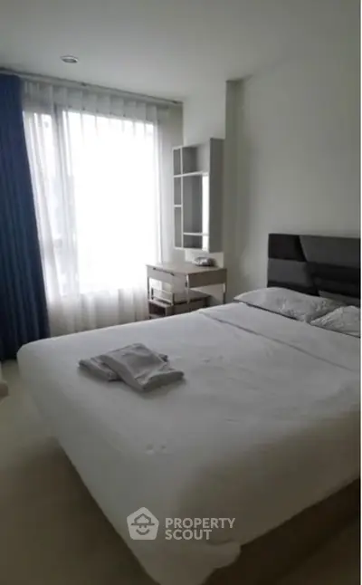 Cozy bedroom with modern decor and natural light from large window.