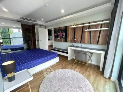 Modern bedroom with stylish decor, featuring a large bed, wooden flooring, and a sleek desk area.