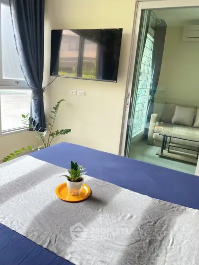 Modern bedroom with TV and balcony access, featuring stylish decor and natural light.