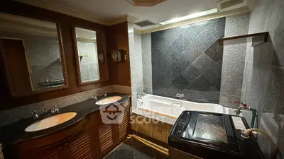 Luxurious bathroom with dual sinks, bathtub, and washing machine in elegant granite setting.