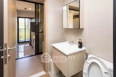 Modern bathroom with sleek fixtures and view into a stylish kitchen with balcony access.