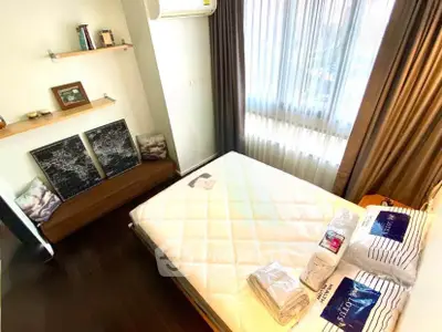 Cozy bedroom with modern decor and ample natural light, featuring a comfortable bed and stylish shelving.