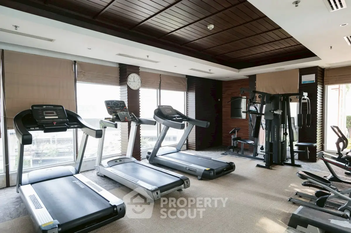 Modern gym with treadmills and fitness equipment in luxury apartment complex.