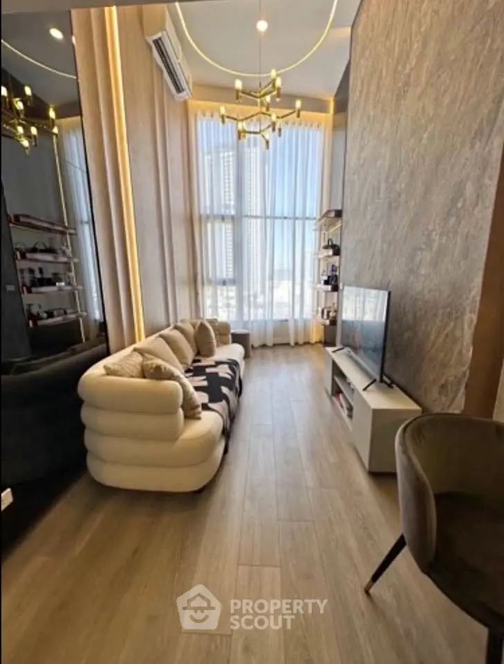 Luxurious modern living room with high ceilings, elegant chandelier, and large windows offering city views.