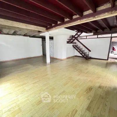 Spacious open-plan room with wooden flooring and staircase, ideal for creative transformation.