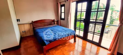 Spacious bedroom with balcony access and wooden flooring in a bright, airy setting.