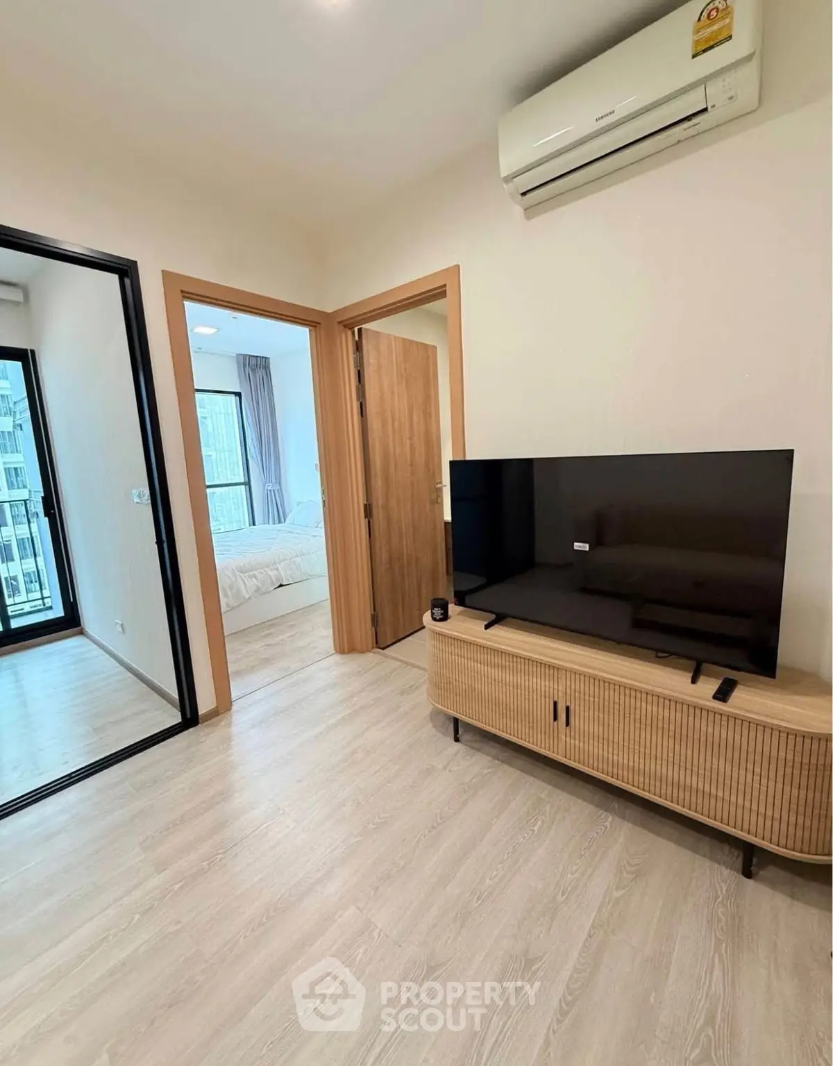 Modern apartment interior with sleek TV setup and cozy bedroom view.