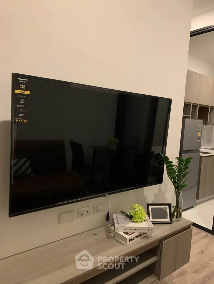 Modern living room with wall-mounted TV and sleek kitchen area
