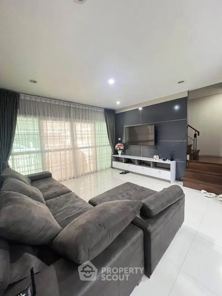 Spacious living room with modern gray sofa and large TV, perfect for relaxation.