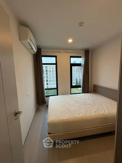Modern bedroom with large windows and city view, featuring minimalist design and air conditioning.