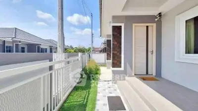 Modern house entrance with stylish door and pathway in sunny neighborhood.