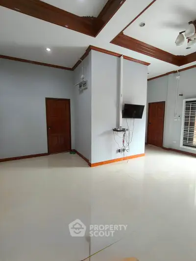 Spacious living room with modern ceiling design and wall-mounted TV, perfect for family gatherings.