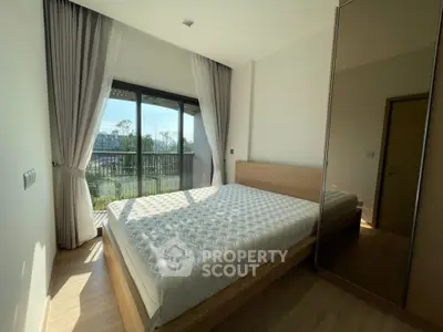 Bright bedroom with large window and modern furnishings, offering a serene view.